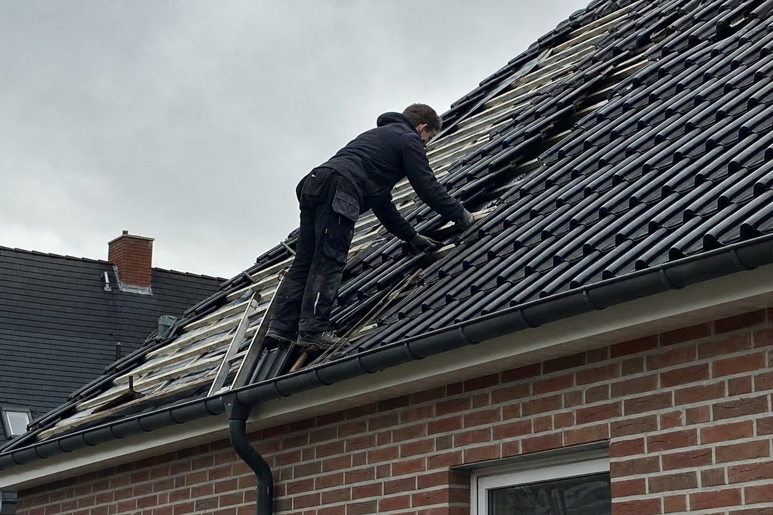 Dacharbeiten an einem eingedeckten Haus, Symbolbild